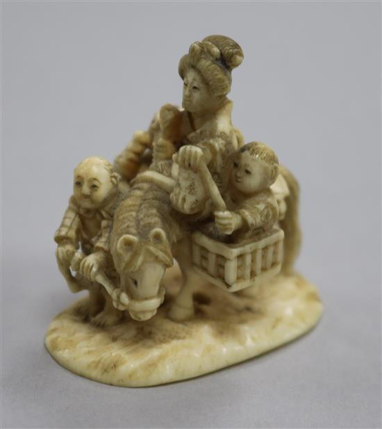 A Japanese carved ivory group of a family travelling with a donkey, height 43mm.